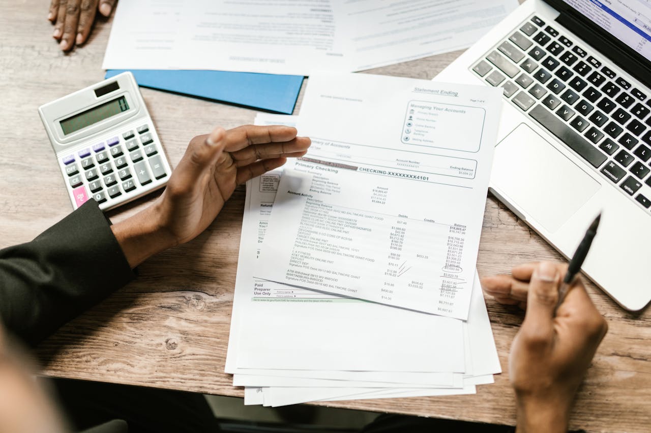 services-02 Hands holding financial documents with calculator and laptop on office desk, business analysis scene.